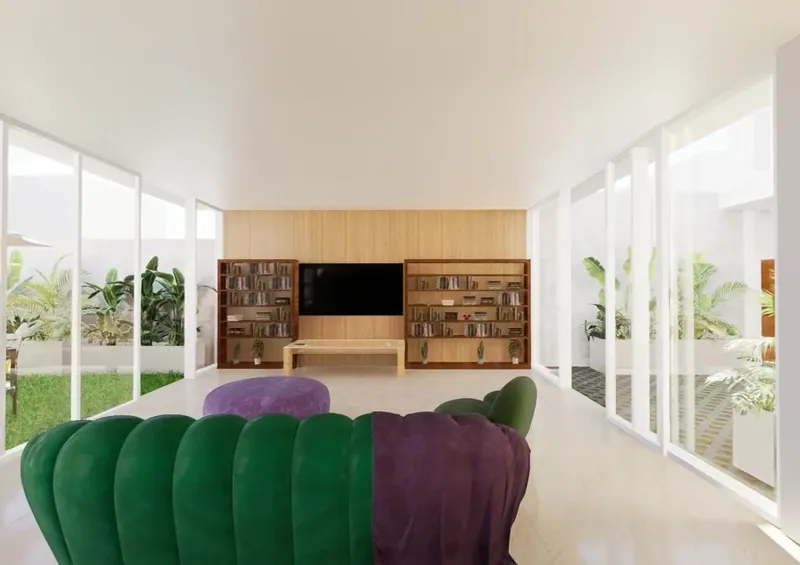 Vivienda con patio: salón abierto al patio ajardinado con sofá verde y librería